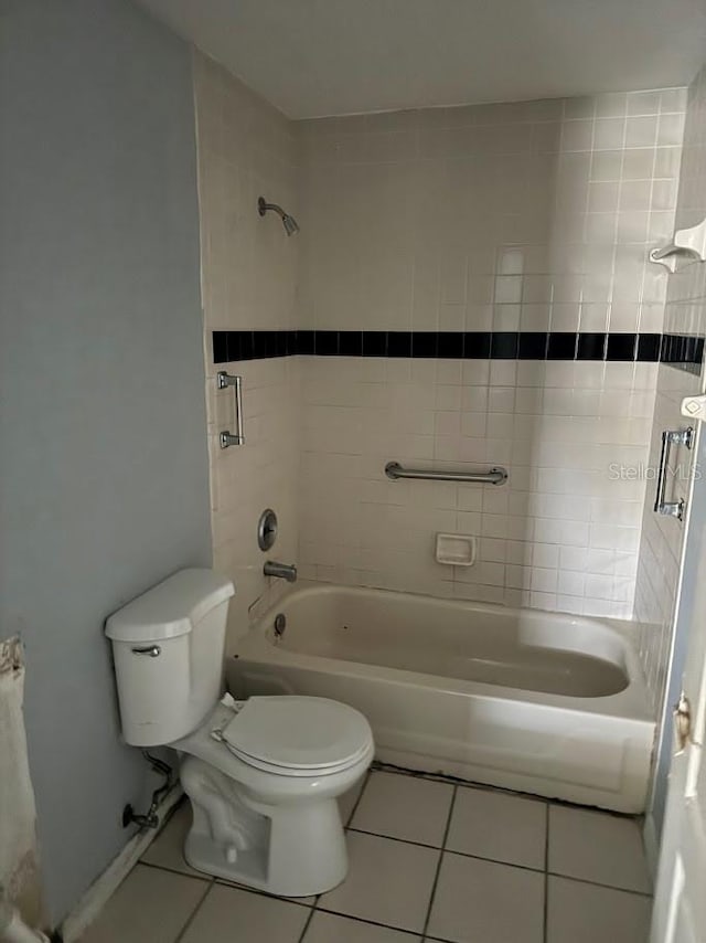 bathroom with tile patterned flooring, toilet, and tiled shower / bath