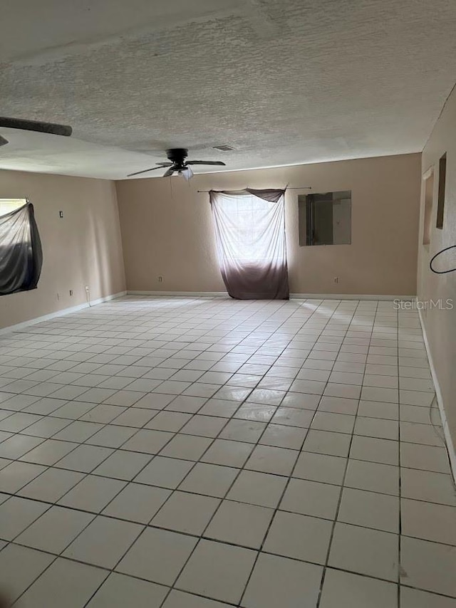 tiled empty room featuring a textured ceiling and ceiling fan