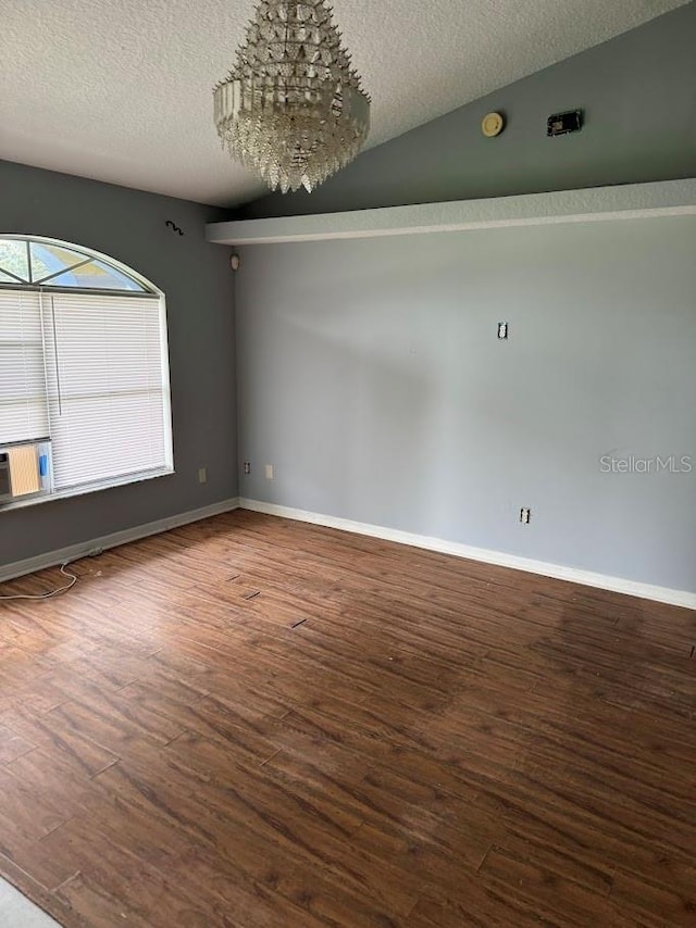 unfurnished room with a textured ceiling, hardwood / wood-style floors, vaulted ceiling, and an inviting chandelier