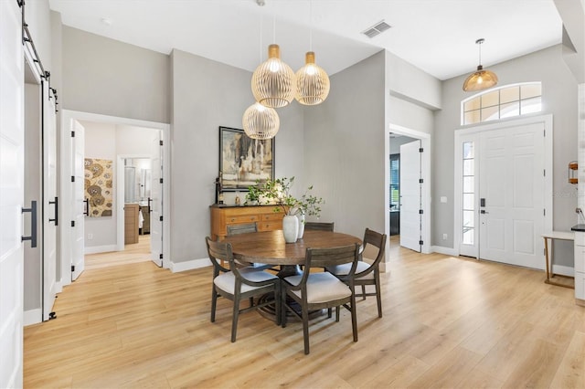 dining room with a barn door and light wood-type flooring