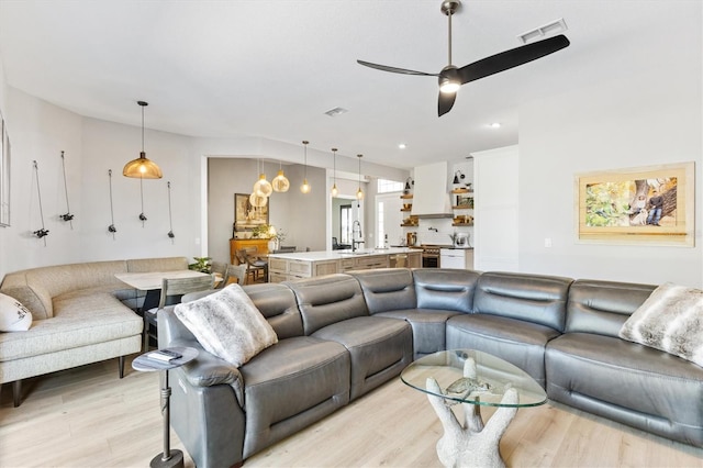 living room with sink, light hardwood / wood-style flooring, and ceiling fan