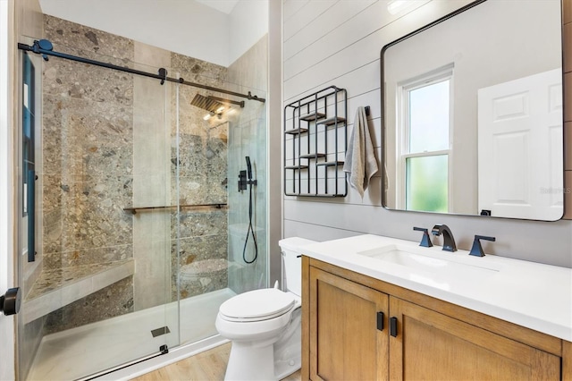 bathroom featuring a shower with door, toilet, wooden walls, wood-type flooring, and vanity