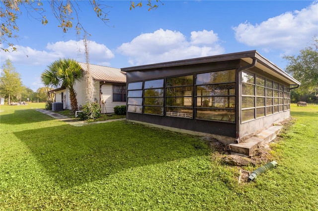 view of side of home with a sunroom, a lawn, and cooling unit