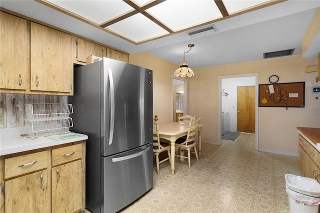 kitchen featuring decorative light fixtures, light brown cabinetry, backsplash, and stainless steel refrigerator