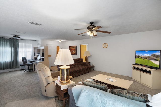 carpeted living room featuring ceiling fan and a textured ceiling