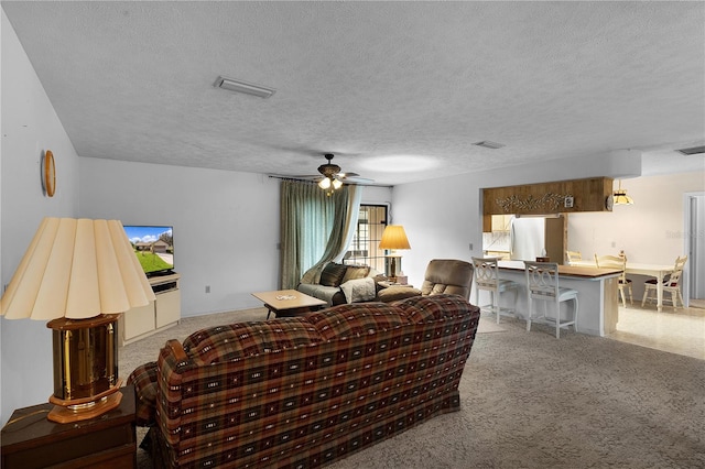 living room featuring a textured ceiling, light colored carpet, and ceiling fan