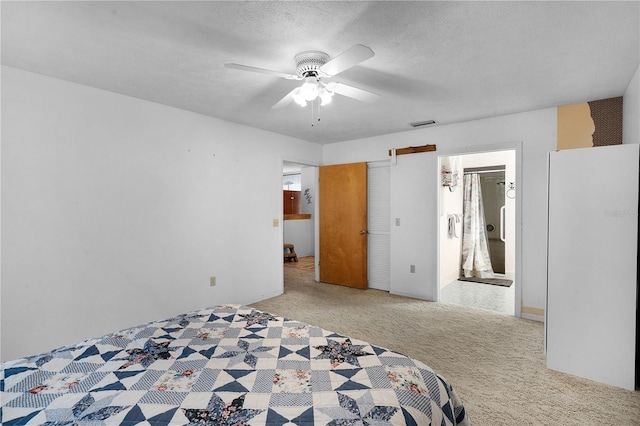 unfurnished bedroom featuring ensuite bath, a textured ceiling, light colored carpet, and ceiling fan