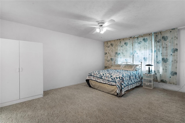 carpeted bedroom featuring ceiling fan and a textured ceiling