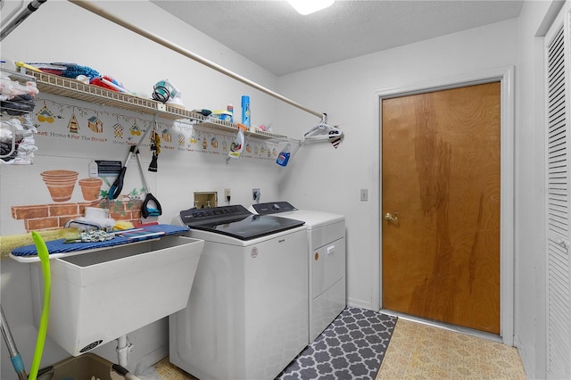 clothes washing area featuring a textured ceiling, sink, and washing machine and dryer