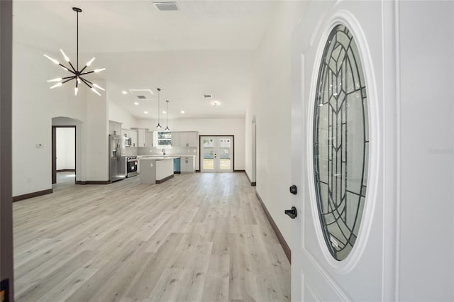 entrance foyer with an inviting chandelier, french doors, sink, and light wood-type flooring