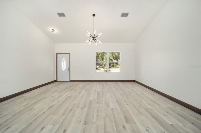 empty room with vaulted ceiling, light hardwood / wood-style flooring, and a notable chandelier