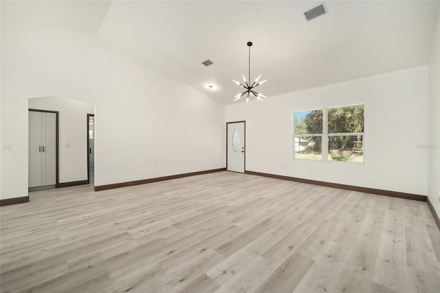 empty room featuring a chandelier, light hardwood / wood-style flooring, and high vaulted ceiling