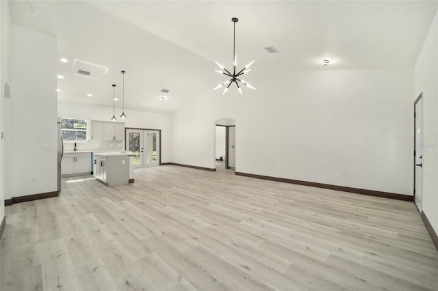 unfurnished living room featuring light hardwood / wood-style floors, a notable chandelier, sink, and high vaulted ceiling