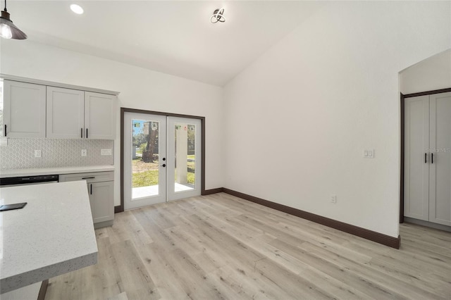 interior space with decorative backsplash, lofted ceiling, french doors, and light wood-type flooring