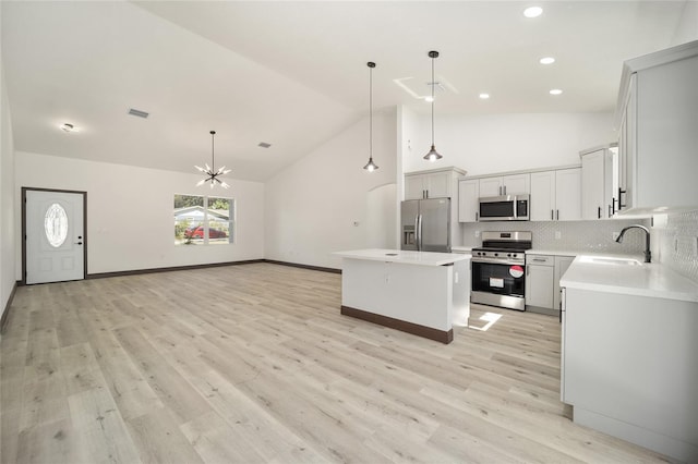 kitchen with a kitchen island, light hardwood / wood-style flooring, decorative light fixtures, and stainless steel appliances