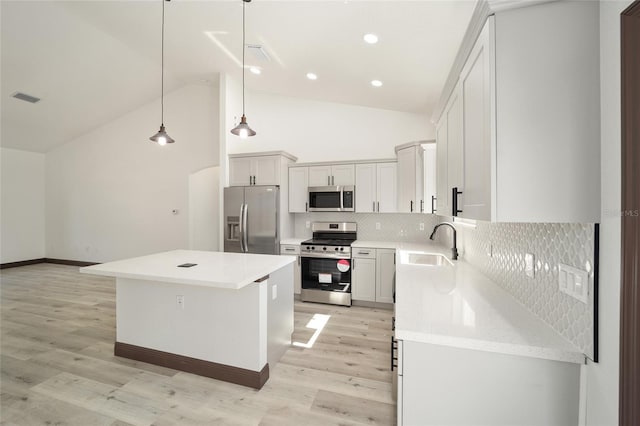 kitchen featuring appliances with stainless steel finishes, light hardwood / wood-style flooring, sink, pendant lighting, and a center island