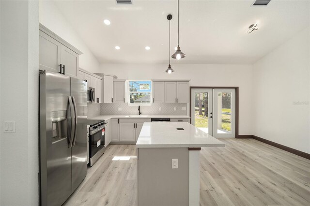 kitchen with stainless steel appliances, a center island, a sink, light wood-type flooring, and decorative backsplash