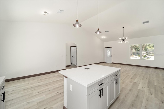 kitchen with a center island, vaulted ceiling, decorative light fixtures, light wood-type flooring, and white cabinetry