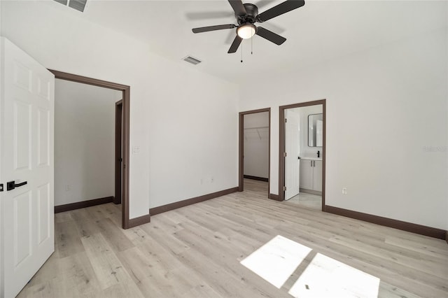 unfurnished bedroom with light hardwood / wood-style flooring, a walk in closet, a closet, and ceiling fan