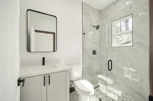 bathroom with toilet, vanity, and a shower with door