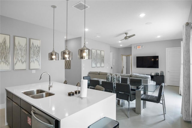 kitchen featuring a center island with sink, sink, decorative light fixtures, stainless steel dishwasher, and ceiling fan