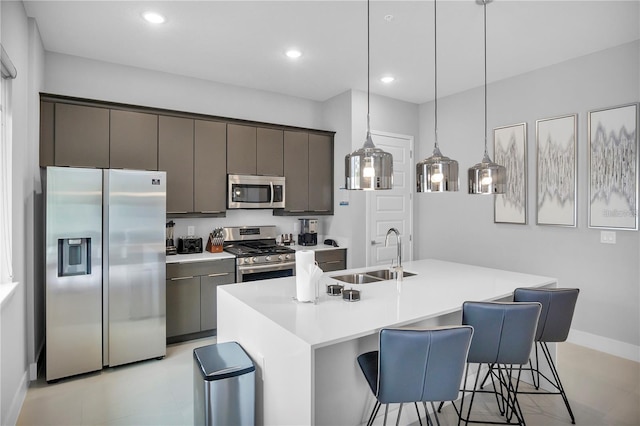 kitchen with dark brown cabinets, hanging light fixtures, a center island with sink, appliances with stainless steel finishes, and sink