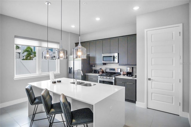 kitchen featuring a kitchen island with sink, a kitchen breakfast bar, sink, pendant lighting, and appliances with stainless steel finishes