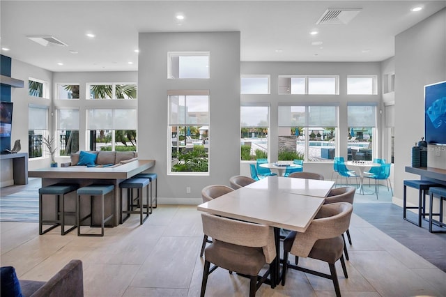 dining space with a towering ceiling and light wood-type flooring