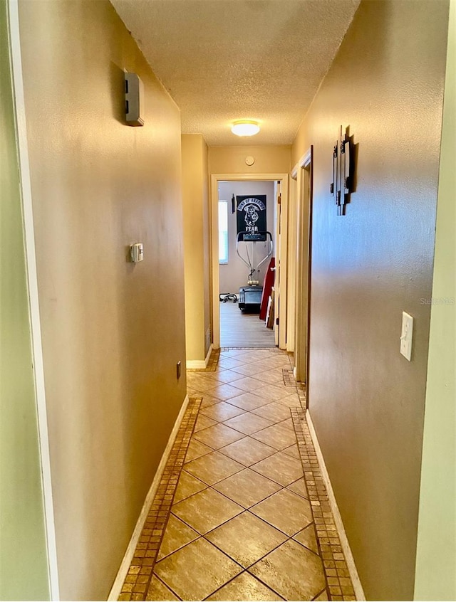 corridor featuring a textured ceiling and light tile patterned floors