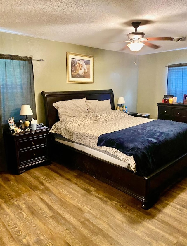 bedroom with light wood-type flooring, a textured ceiling, and ceiling fan