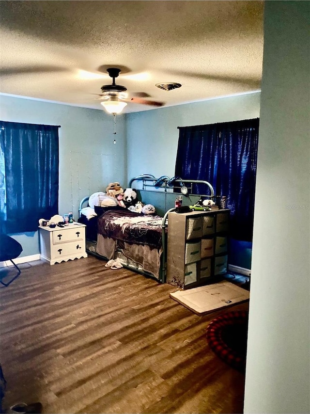 bedroom with wood-type flooring, ceiling fan, and a textured ceiling