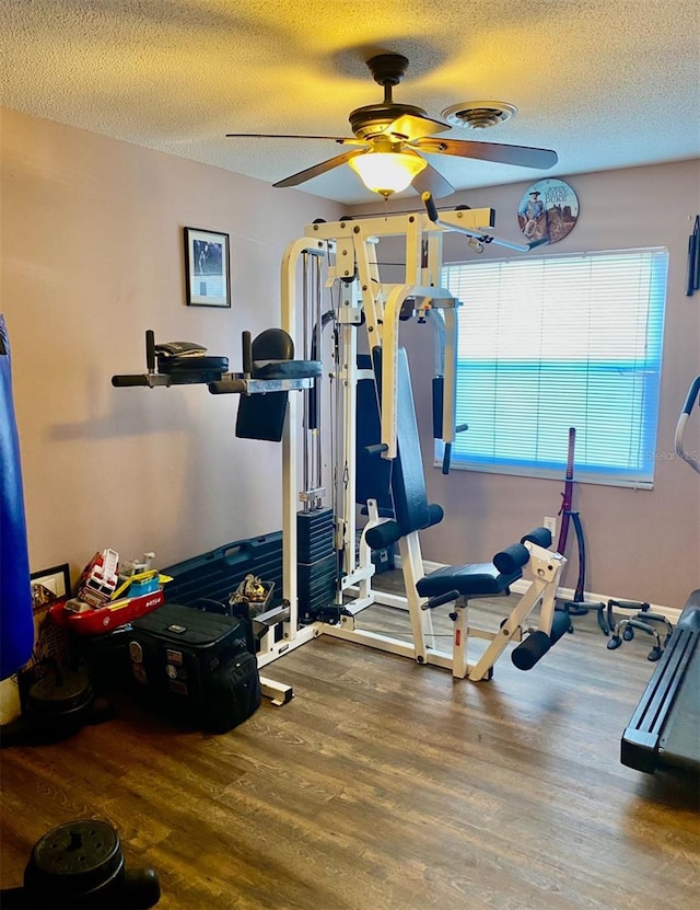 workout room with hardwood / wood-style floors, ceiling fan, and a textured ceiling