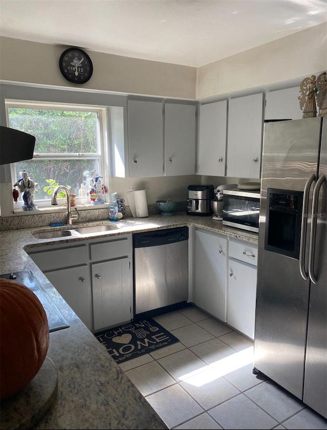 kitchen with white cabinets, appliances with stainless steel finishes, sink, and light tile patterned flooring