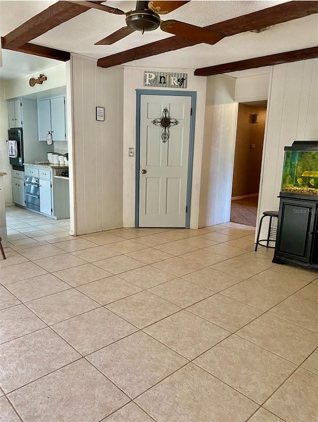 tiled entryway featuring a textured ceiling and ceiling fan