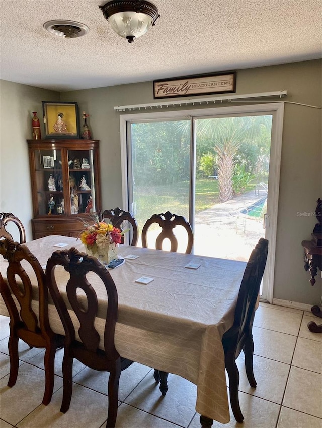 dining room with a textured ceiling and light tile patterned flooring