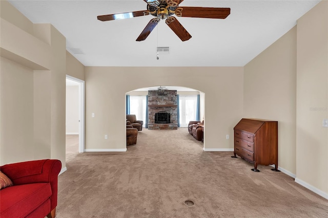 living room featuring light colored carpet, ceiling fan, and a fireplace