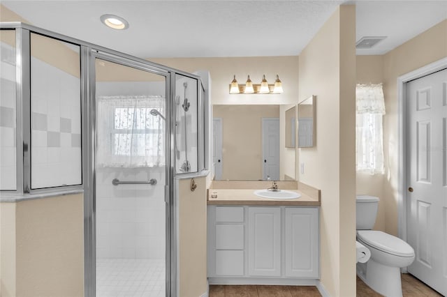 bathroom featuring a shower with door, vanity, toilet, and tile patterned floors