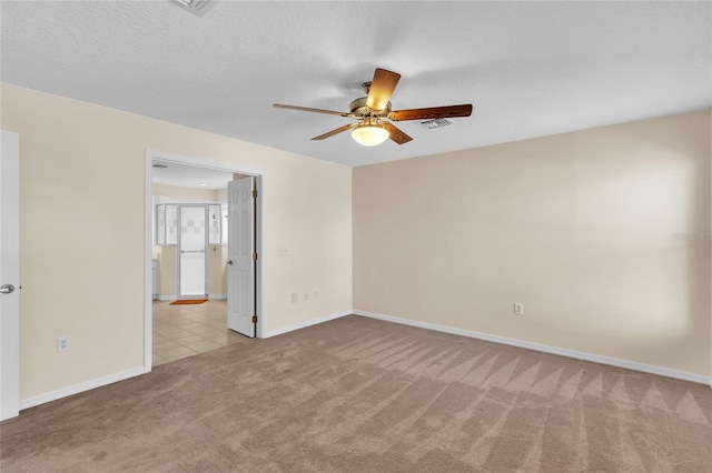 spare room featuring light carpet, a textured ceiling, and ceiling fan