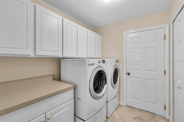 clothes washing area with a textured ceiling, washing machine and clothes dryer, and cabinets