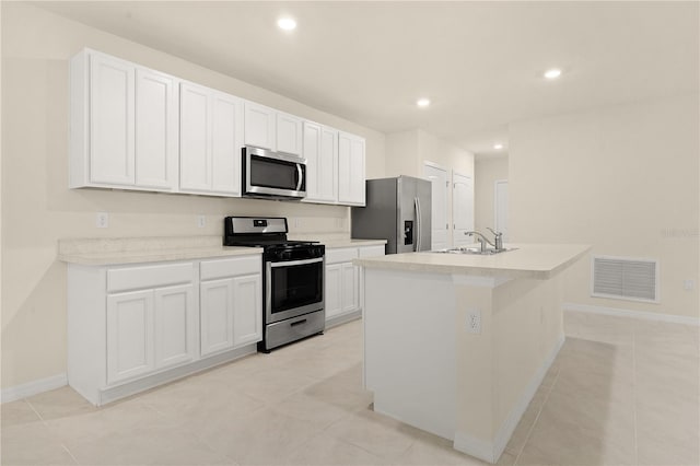 kitchen with sink, white cabinetry, a center island with sink, light tile patterned floors, and appliances with stainless steel finishes