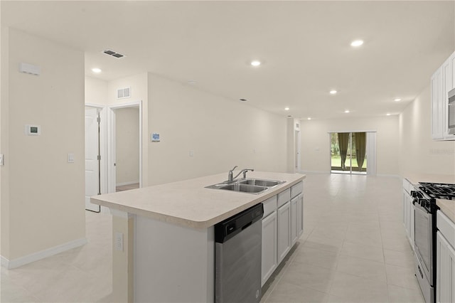 kitchen featuring sink, a center island with sink, light tile patterned floors, appliances with stainless steel finishes, and white cabinets