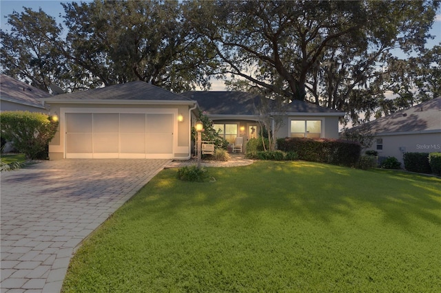ranch-style house with stucco siding, an attached garage, decorative driveway, and a front yard