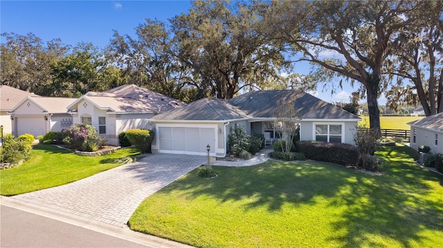 single story home with an attached garage, decorative driveway, fence, and a front yard