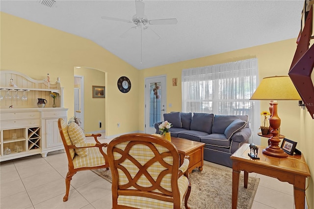 tiled living room featuring ceiling fan, a textured ceiling, and lofted ceiling