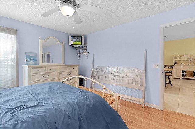 bedroom featuring a textured ceiling, light wood-type flooring, and ceiling fan