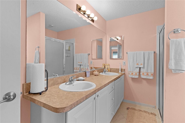 bathroom featuring vanity, a textured ceiling, a shower with shower door, and tile patterned flooring