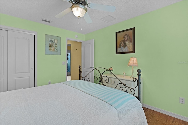 bedroom with a closet, a textured ceiling, wood-type flooring, and ceiling fan