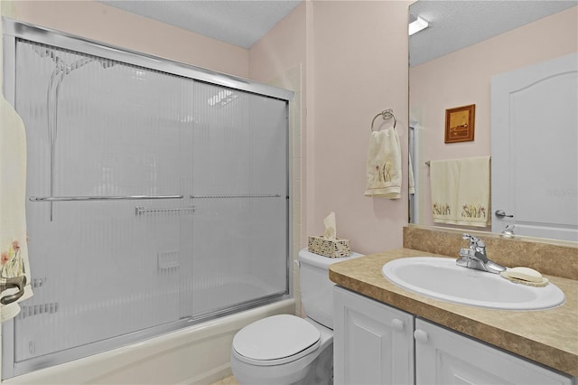 full bathroom featuring toilet, combined bath / shower with glass door, a textured ceiling, and vanity