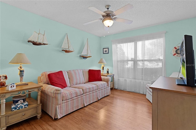 living room featuring light hardwood / wood-style flooring, a textured ceiling, and ceiling fan