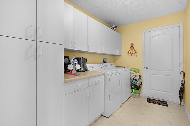 clothes washing area with cabinets, a textured ceiling, and washer and clothes dryer